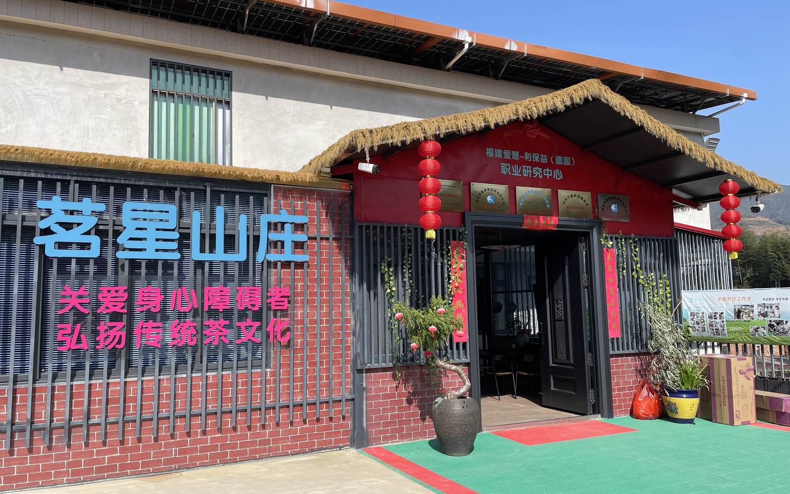 The entrance of Aihui Mingxing Mountain Lodge in Anxi, with its name board, red lanterns and thatched eave