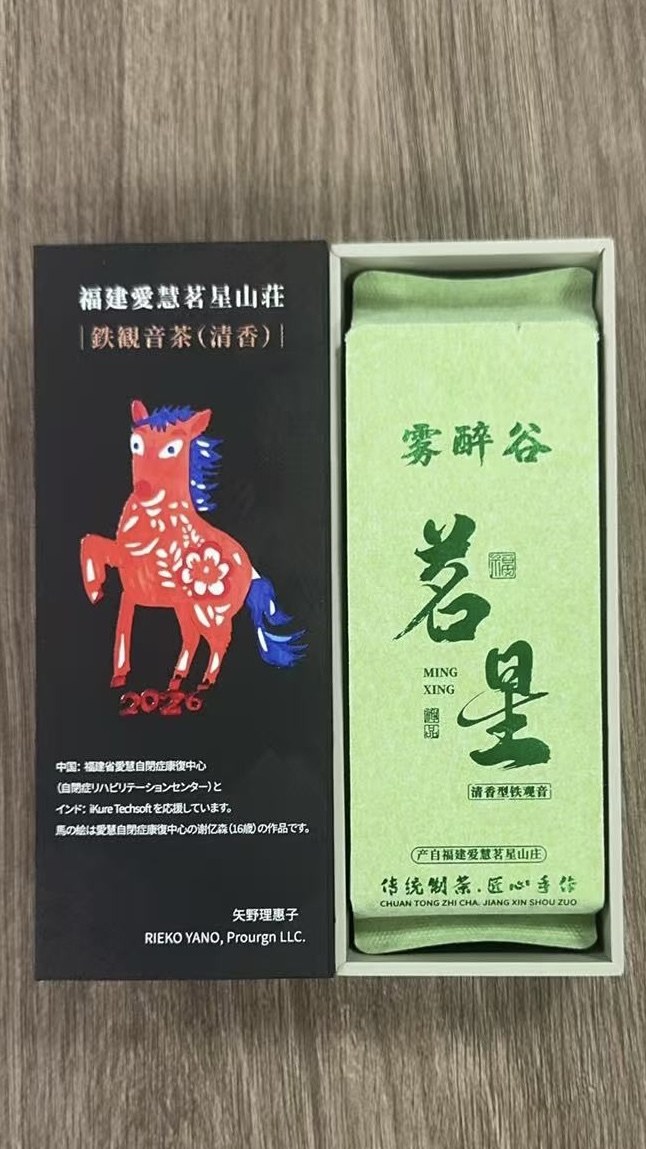 Rieko's gift box opened: the lid carries the 2026 horse painted by a member of Aihui, and a foil pouch of Mingxing Tieguanyin sits in the tray