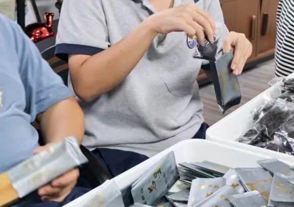 Aihui members filling and stacking small pouches of Tieguanyin tea by hand at the tea studio