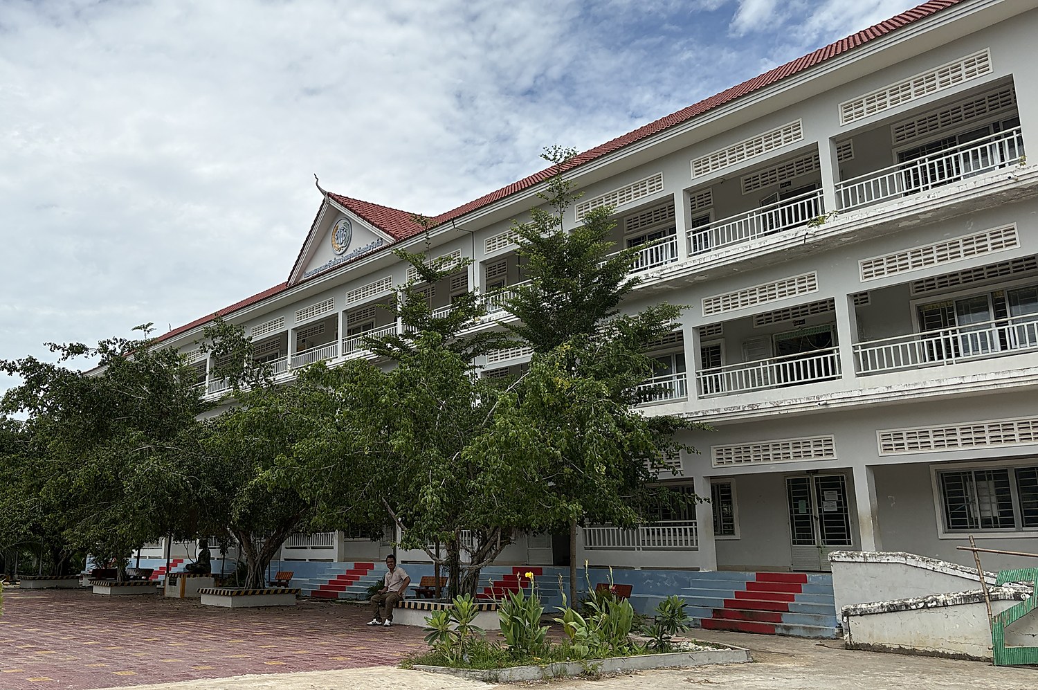 The school grounds at Kampong Trabek in Prey Veng, seen from the courtyard, with the upper secondary block behind the trees