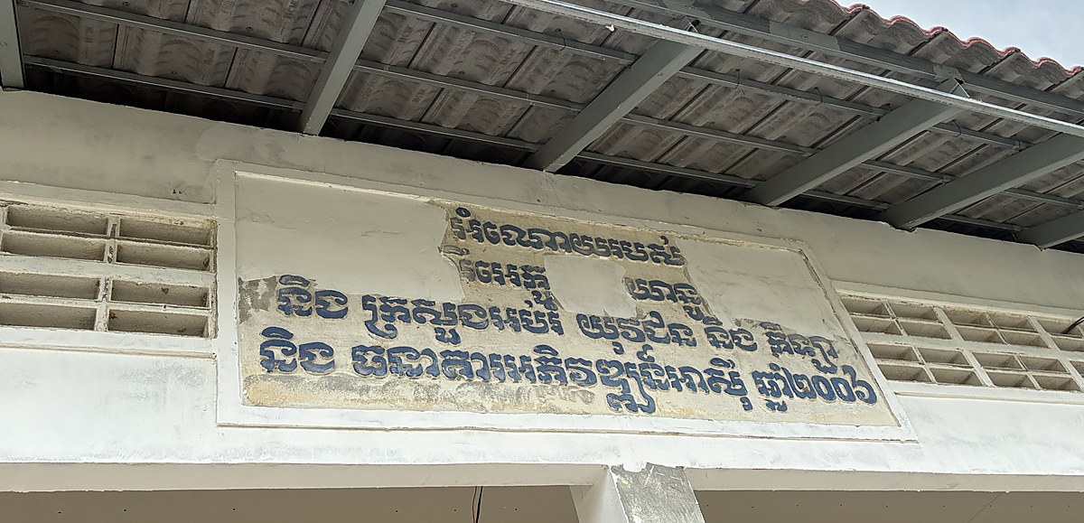 A painted plaque in Khmer on the gable of the school block, ending with the year 2006