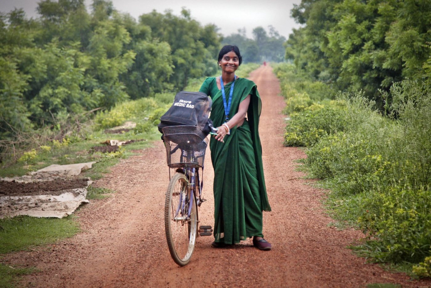 An iKure community health worker setting out for a village with her medic bag on her bicycle