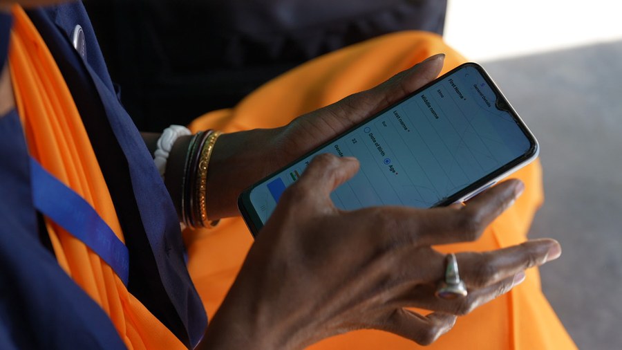 An iKure health worker entering a patient's details into the WHIMS app on her phone