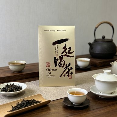 A larger champagne gold box of the same series, a white gaiwan and a cup of tea beside it