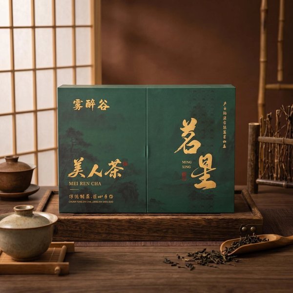 A flat deep green two-panel gift box lettered 美人茶 and 茗星 in gold, in front of a paper screen