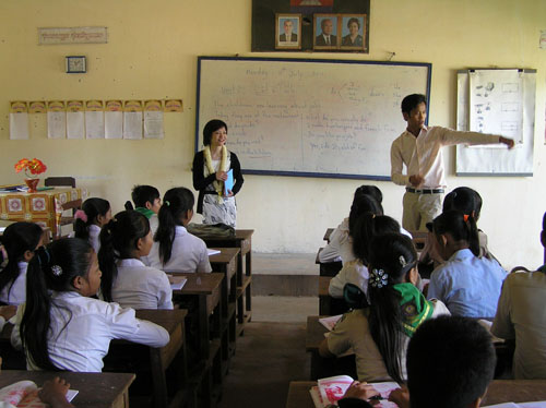 An English lesson at the school: a teacher at the whiteboard and students at wooden desks